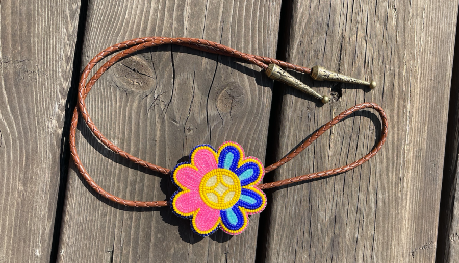 A beaded pink, yellow and blue flower is the clasp on a bolo tie, a looped leather cord with metal ends.
