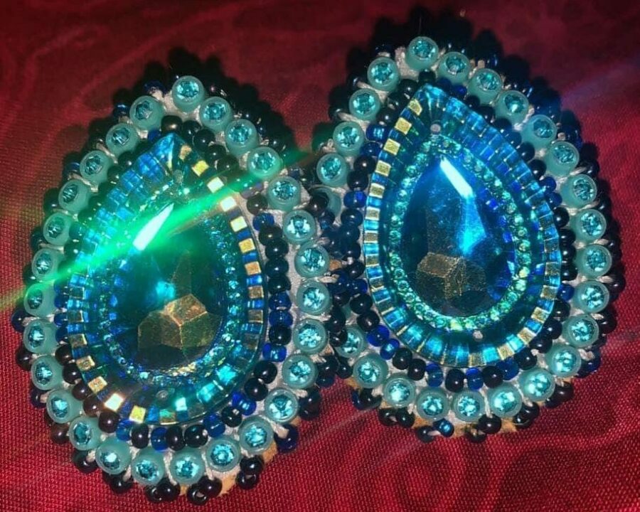 Two tear-drop shaped beaded earrings made with a variety of blue beads of different sizes.