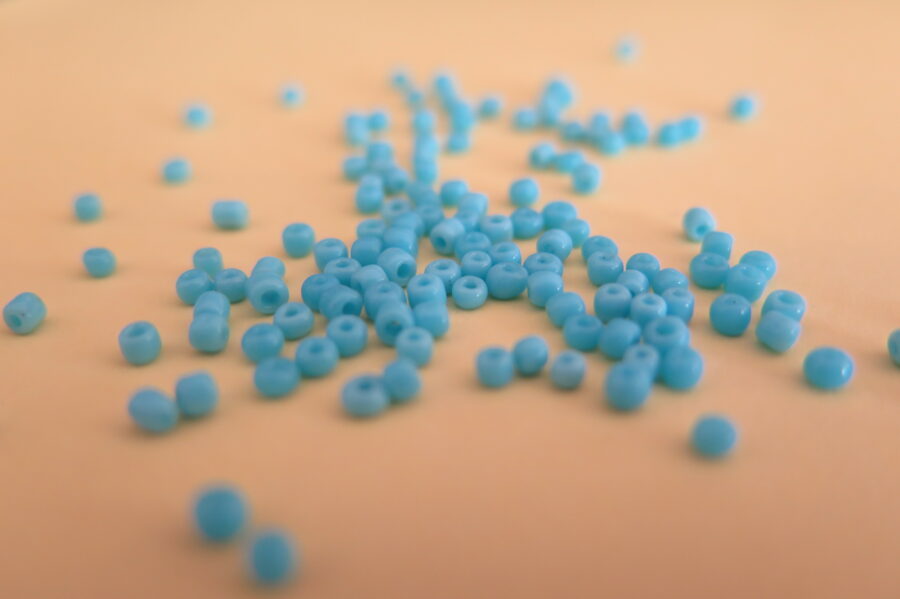 Close up of blue beads on an orange surface.