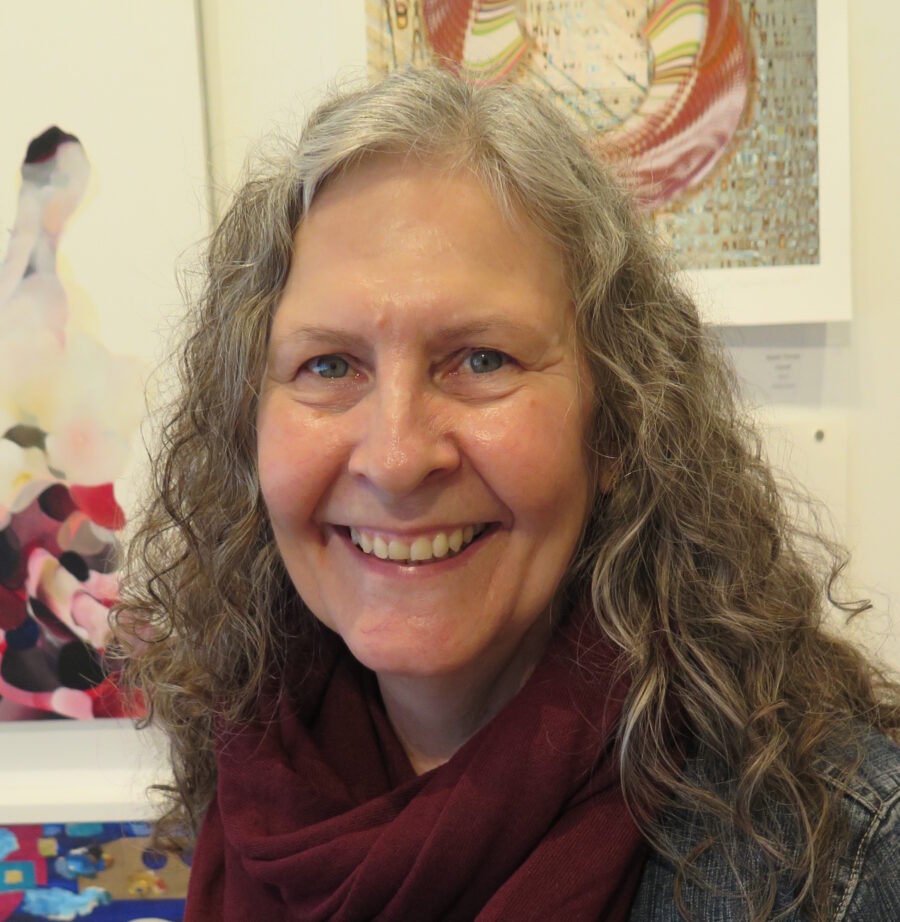 Headshot of Jennine Krauchi, a Metis woman with long curly grey hair looking at the camera and smiling.