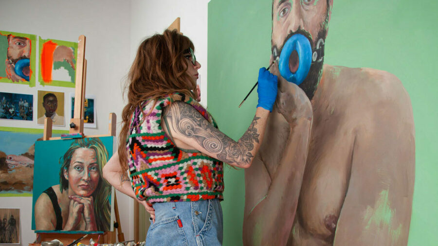 Laura Lewis works on a large figurative painting in her studio.