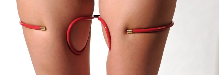 Photo of a person's bare thighs. Anastasia Pindera's wearable sculpture partially encircles each thigh. The sculpture is metal about the diameter of a pencil that fits around the thighs.