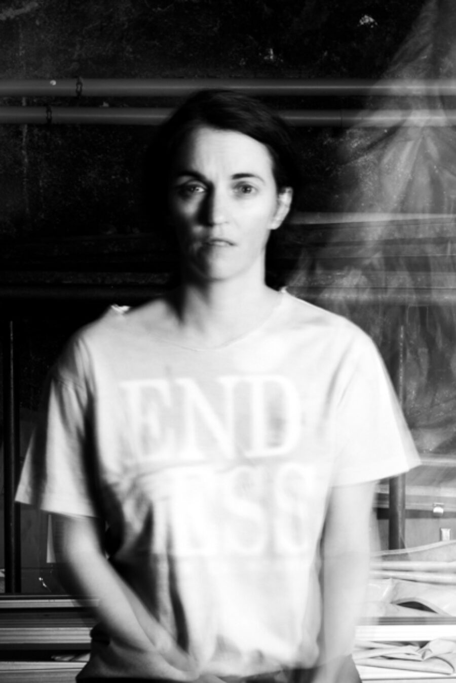 Black and white photo of Estelle Chaigne using what looks like analog film. Her arms are blurry from moving while the picture was taken. She is wearing a light coloured t-shirt.