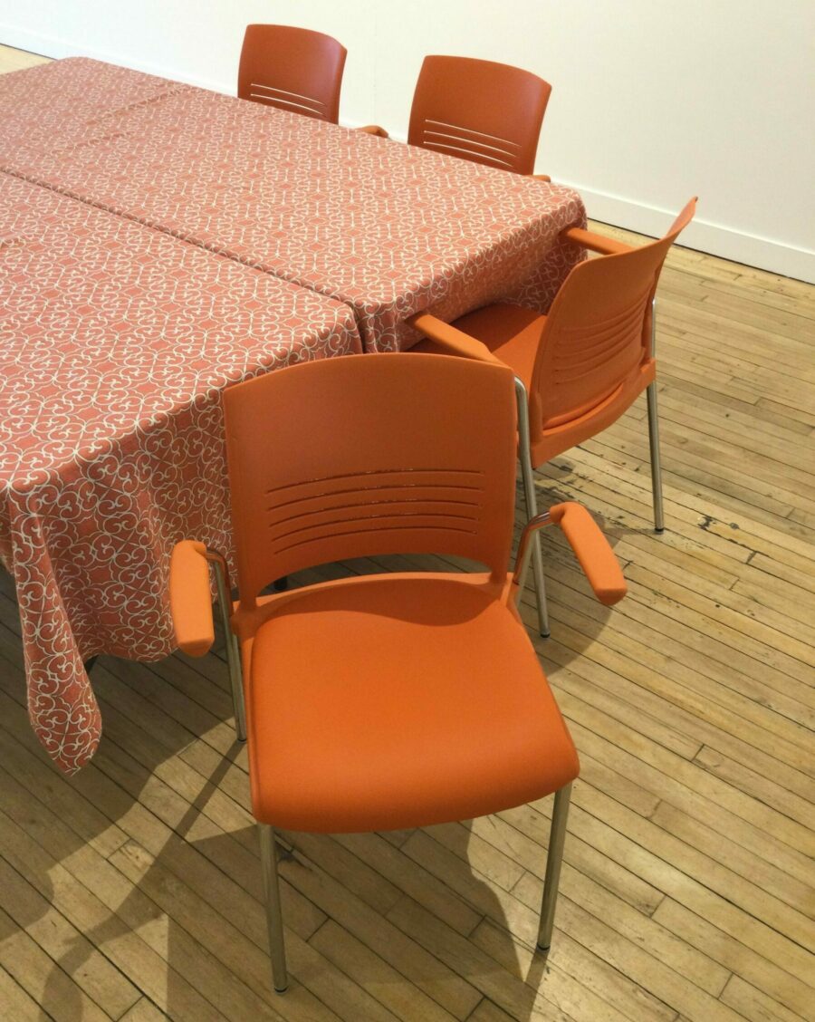 An orange chair with arm rests and a cushioned seat.
