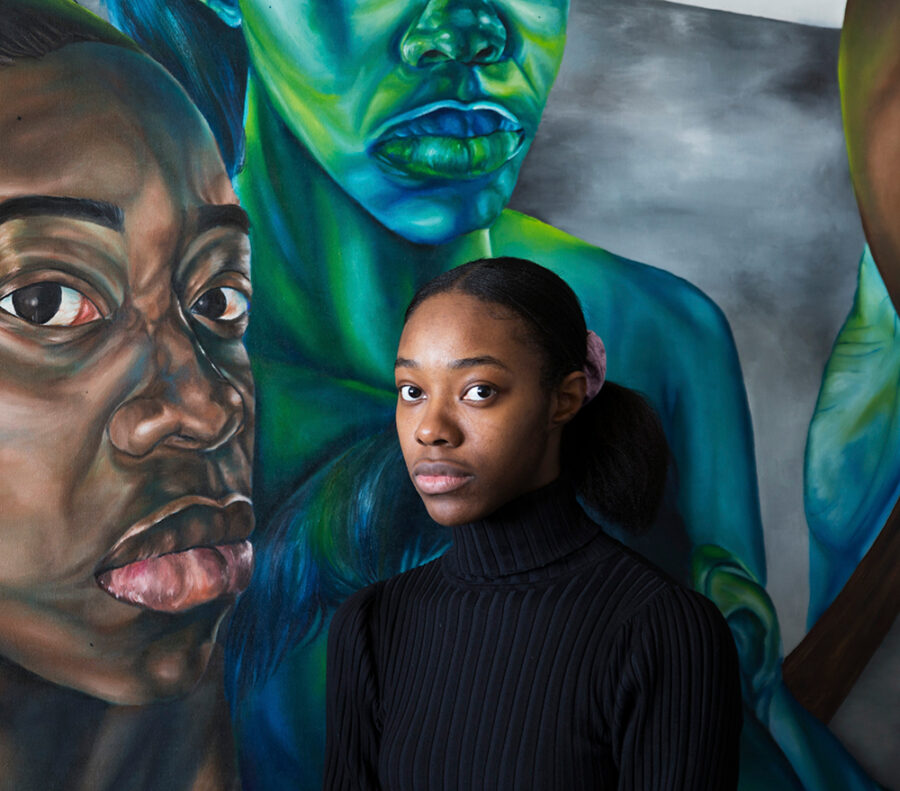 Photo of Ekene Maduka, panel moderator standing in front of one of her paintings.