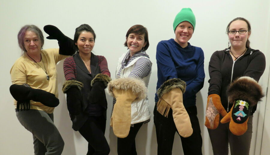 Five people standing in a line showing off the gauntlet mittens they made.