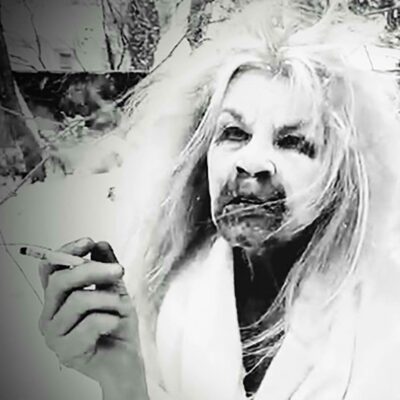 Black and white photograph by Susan Aydan Abbott of a woman smoking a cigarette outdoors in the snow. She has messy unbrushed hair and a black substance staining the area around her mouth.