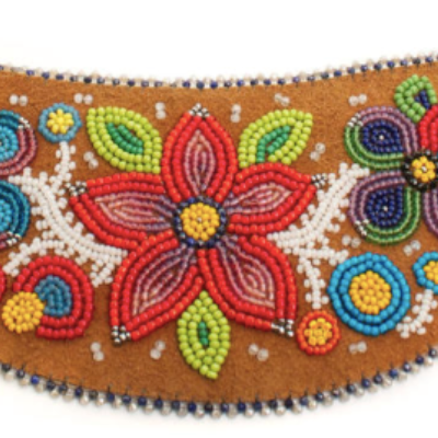 Beaded flower design on a piece of leather that is shaped like a bean.