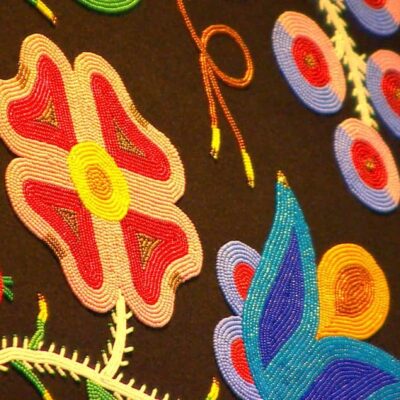 Close up of colourful flower beadwork on black fabric.
