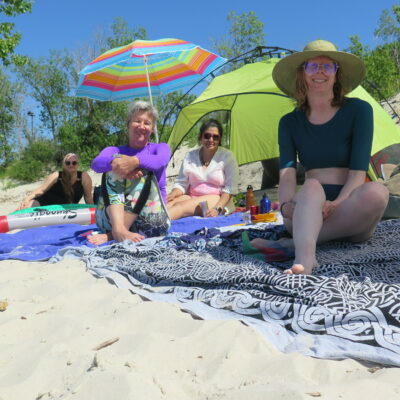 Four people sitting on a sunny beach.