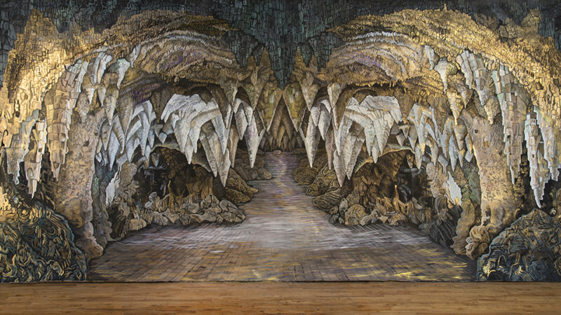 Large scale painting by Bev Pike depicting the interior of a cave with many stalactites.