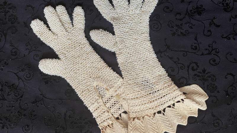 A pair of white beaded gloves on a black background