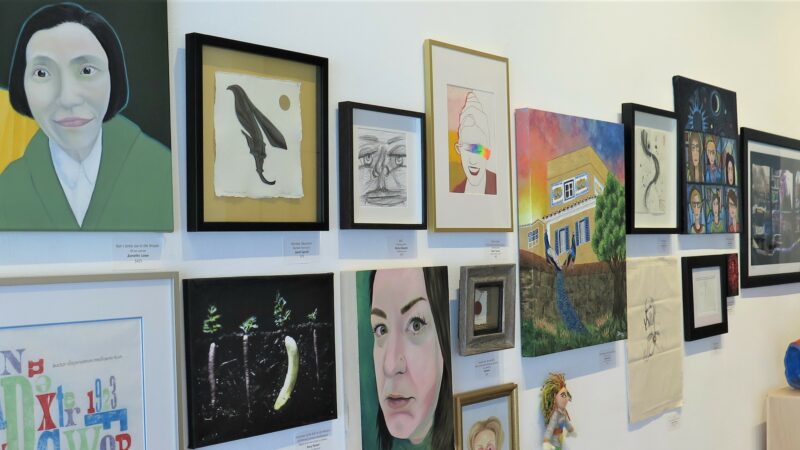 Many artworks by MAWA members hanging on a white wall.