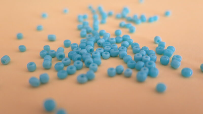 Close up of blue beads on an orange surface.