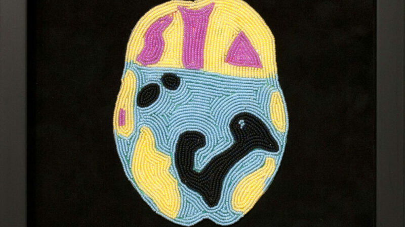 Beaded image of a brain scan in yellow, pink and blue on black cloth.
