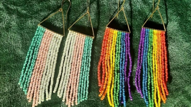 Two sets of fringe earrings one with blue, pink and white stripes and the other with rainbow colours.