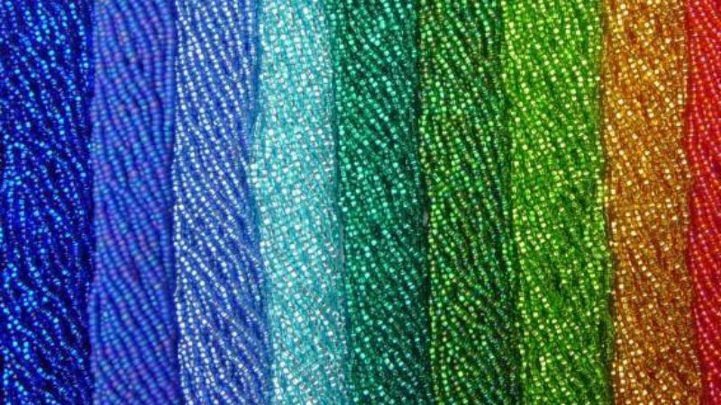 Strands of seed beads of different colours. Going from blue beads on the left to red on the right.