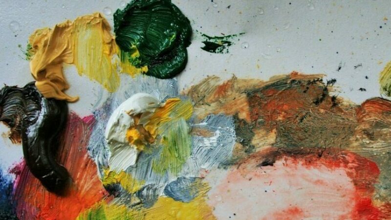 Blobs and smears of different coloured paint on a white palette.