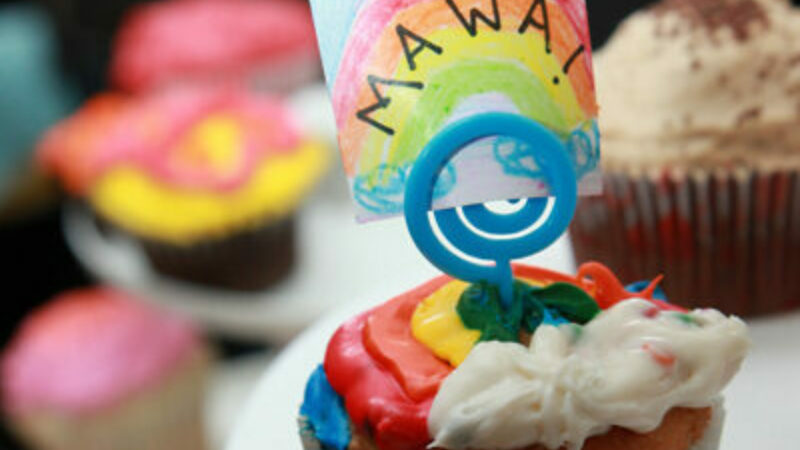 A cupcake with rainbow coloured icing.