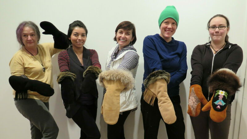 Five people standing in a line showing off the gauntlet mittens they made.