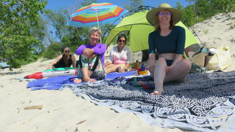 Four people sitting on a sunny beach.