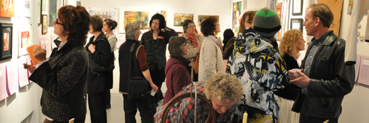 A group of people looking at artwork on the walls of the MAWA space.