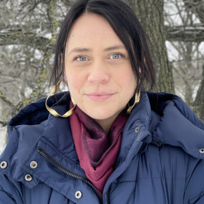Headshot of Anastasia Pindera standing outside in front of a tree without leaves.